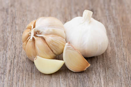 Close up garlic bulb and cloves isolated on rustic wood table background. Healthy food or herbal natural medicine plant concept. Vintage tone.の写真素材