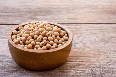 Closeup soy beans in wooden bowl  isolated on old rustic wood table background. Natural protein concept. Vintage style.の写真素材