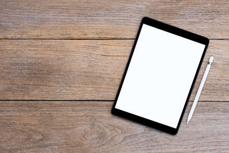 Mockup image of black tablet computer pc with blank white screen with pencil isolated on wood table...