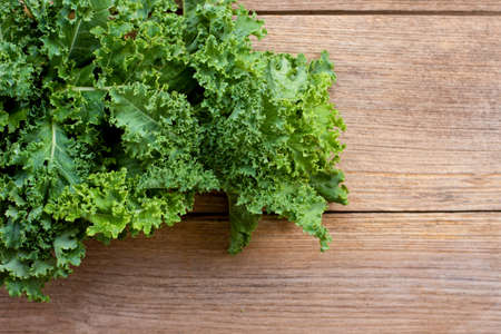 Closeup fresh green curly Kale cabbage vegetable leaves isolated on wood table background.の写真素材