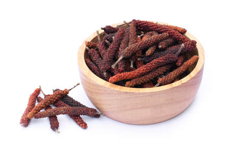Closeup dry Idian long pepper or Piper longum  in wooden bowl isolated on white background. Herbal medical plant concept.の写真素材