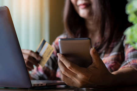 Asian young woman hands holding credit card, using mobile smartphone for online shopping and payment...