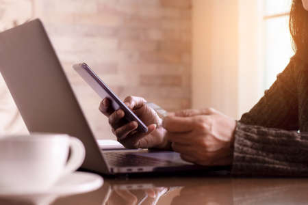Woman hand holding and using mobile smartphone and credit card for online shopping and payment at...