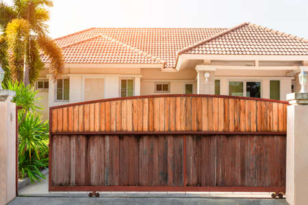 Electric automatic sliding wooden door or garage with modern home background. Auto gate and remote...