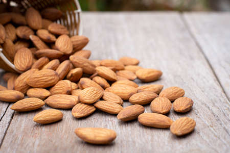Almond nuts in wooden basket isolated on wood table background.の写真素材