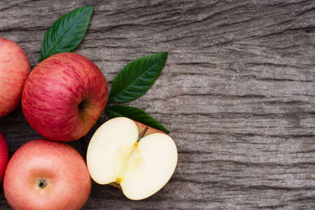 Pink fuji apple with cut in half slice and green leaf on wood table background. Top view. Copy space...