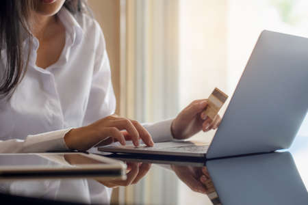 Business woman hand holding credit card and typing on laptop computer keyboard for online shopping...