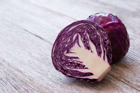 Closeup red cabbage with cut in half slice isolated on wooden table background.