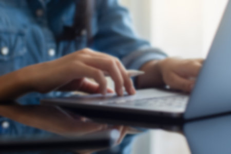 Blurred image of casual woman hand typing on laptop computer at workplace.の写真素材