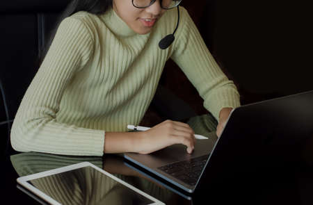 Young asian woman with headphone work on laptop computer at workplace. Customer service, telework, online working, teleconference concept.の写真素材