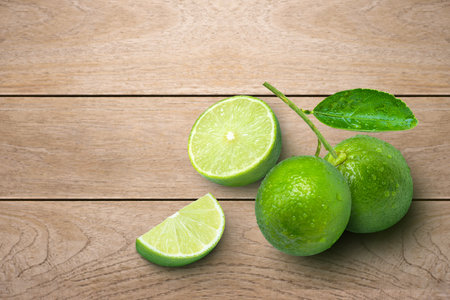 Lime fruits with green leaf and cut in half slice isolated on wooden table background. Top view....