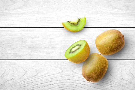 Kiwi fruit with half slice isolated on white wooden table background. Top view. Flat lay. Copy space.の写真素材
