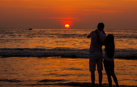 Silhouette of Romantic couple on the beach enjoying sunsetの写真素材