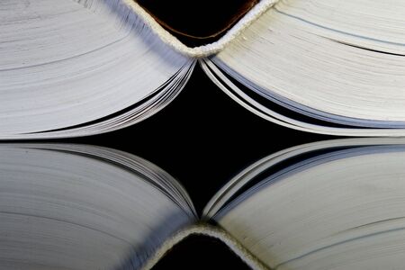 Spine of an opening book on the mirror with black background.の写真素材