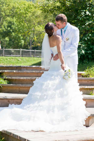 Bride and groom kissing and hugging on greenの写真素材