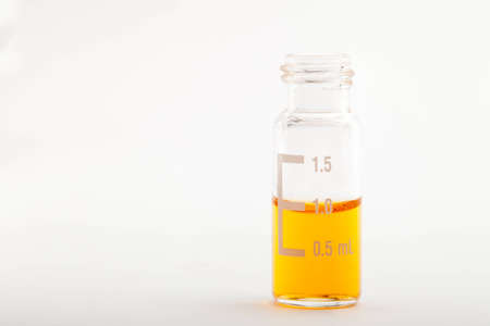 Single chromatographic glass vial filled with one milliliter of orange liquid  Isolated on whiteの写真素材