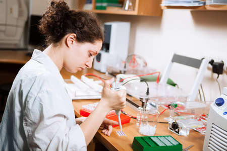 Female researcher in a lab performs sample preparation for DNA electrophoresis making dots of ethidium bromideの写真素材
