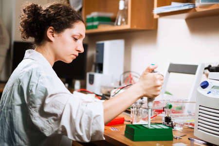 Female researcher in a lab performs sample preparation for DNA electrophoresis making dots of ethidium bromideの写真素材