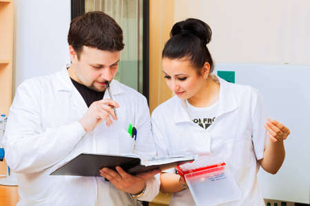 Two scientists with lab journal discussing results of experimentの写真素材
