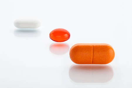 Extreme close-up view of three various pills  orange, red oil capsule and white oneの写真素材