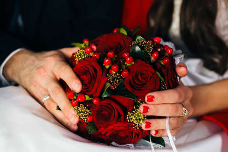 Wedding bouquet of red roses held in bride s and groom s handsの写真素材
