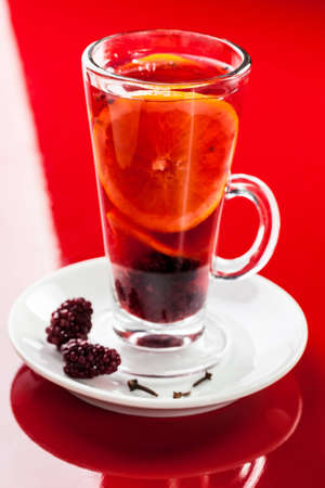 Hot drink with blackberry, orange slices and clovesの写真素材