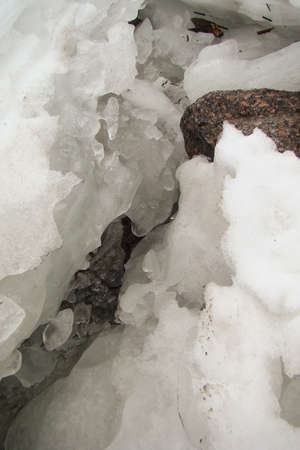 deep crack in a thick layer of ice with a stone