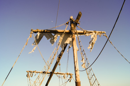 Mast of the old ship with torn sails