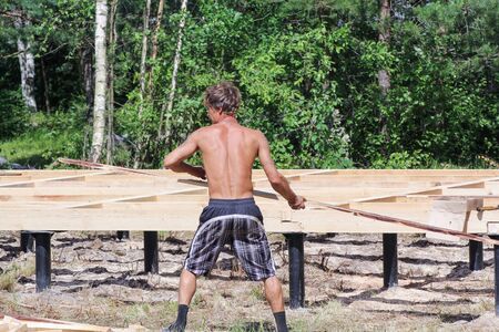Working with a board in the hands. Leningrad region, Russia - 29 June, 2015. Construction of country houses and cottages.のeditorial素材