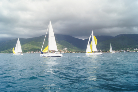 Yachts on the background of dark hills. Sea race on yachts in the Bay of Kotor Adriatic Sea.のeditorial素材