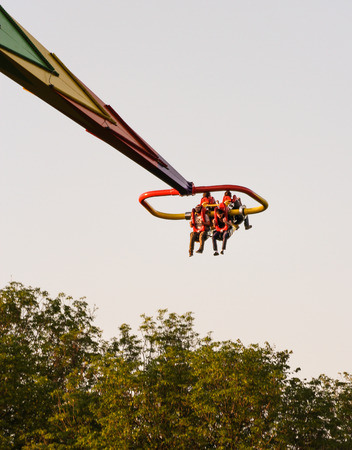 People flying over trees. Amusement and extreme rides for teenagers and adults.のeditorial素材