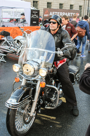 Biker on black bike between people. The annual International Festival of Motor Harley Davidson in St. Petersburg Ostrovsky Square.のeditorial素材