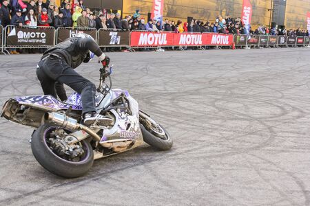 A biker lifting a motorcycle. Sports motorcycle show of bikers on the open area.のeditorial素材