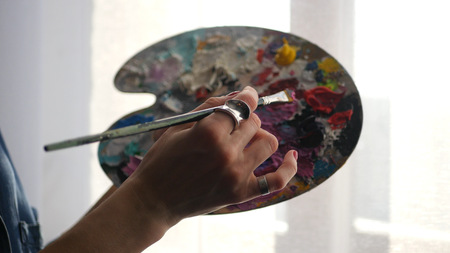 young artist mixes paint on a brush color politrila, HDの写真素材