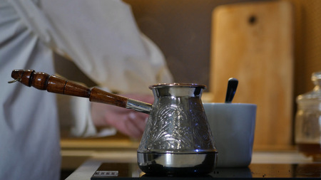 Early in the morning the girl poured coffee in a Turkish, in a white cup, blowing, that would rather cool down. HDの写真素材