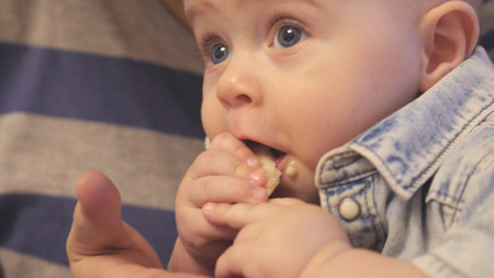 The kid sits in the arms of his father and he eats a piece of apple.. hdの写真素材