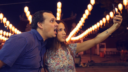A friend is photographed on the phone at night with beautiful lanterns. The man is fooling around at...