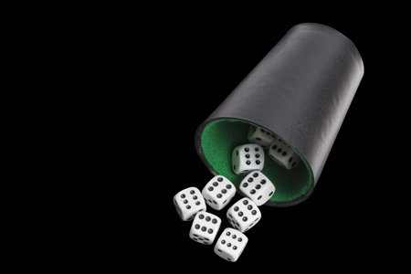 Black glass with white dice on a black background.の写真素材