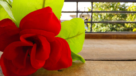 Closeup Artificial red rose flower with dark shed background on woodの写真素材