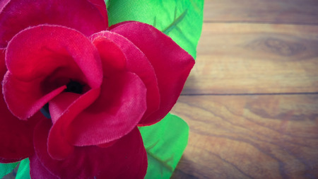 Closeup Artificial red rose flower with dark shed background on woodの写真素材