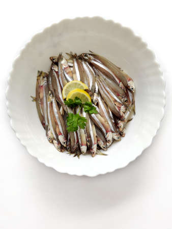 Fresh Anchovy fish decorated with Lemon slice and herbs on a white Plate,White Background.