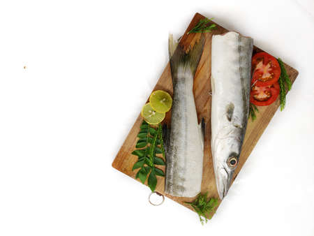 Fresh raw Barracuda Fish (cheelavu) head and body decorated with herbs and vegetables on a White...