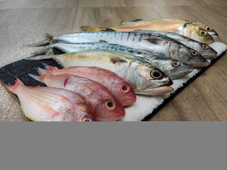 Selective focus of various fishes decorated on a wooden pad.fish online marketing concept.