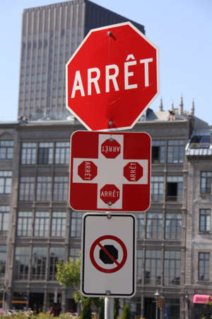 octagonal red and white stop street sign with French text (arrÃªt = stop) and square red and white sign indicating crossroad with 4 stop signs (each with french text arrÃªt = stop)の写真素材