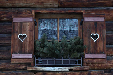 log cabin window with old fashioned wooden shutters with heartsの写真素材