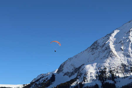 paraglider in the blue sky with a snow covered mountain in the background