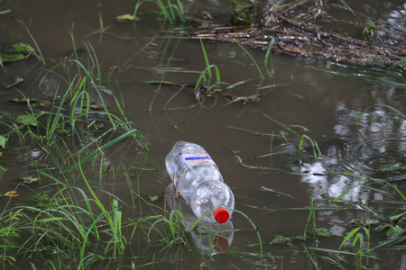 discarded single-use plastic bottle floating in the waterの写真素材