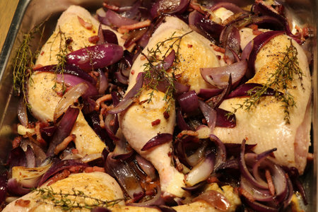 chicken legs covered with glazed red onions and figs in an oven trayの写真素材