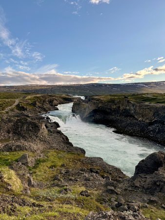wild Skalfandafljot river running through a volcanic landscape with Godafosss waterfall in the distance cast in the soft light of the golden hourの写真素材