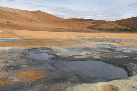 colorful geothermal landscape of namaskard, iceland, with dark gray scalding hot mud pools in the...